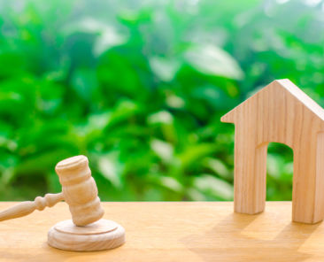 Wooden house and hammer of the judge on a green background. Concept trial property. The court decision on the transfer of property, the nationalization of property. The right to property